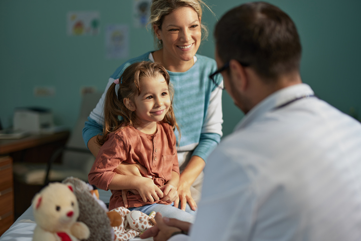 Smiling girl having an appointment with her mother at pediatricians'.